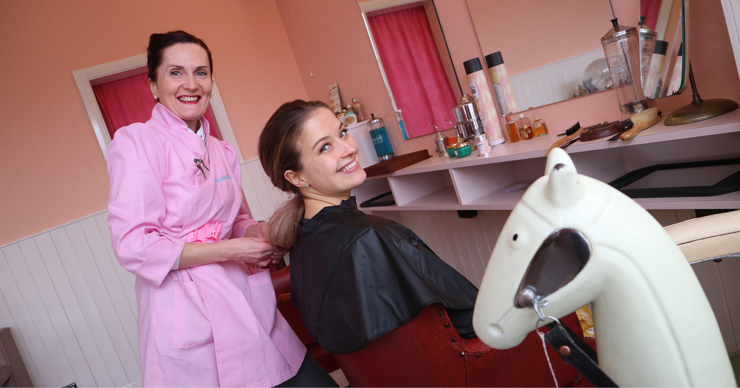 Woman styling another woman's hair inside the 1950s salon at Beamish Museum